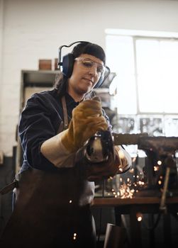Smoothing it out. an attractive young female artisan using an angle grinder in her workshop.