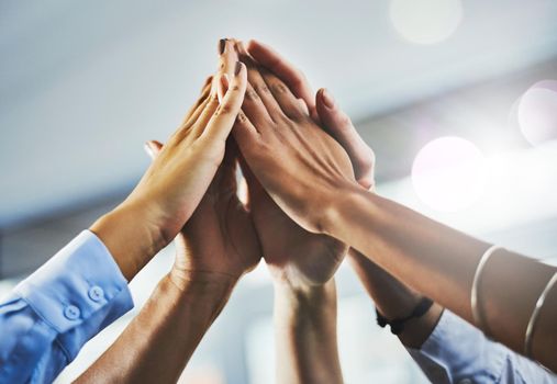 If we stand as a team, we will succeed. Closeup shot of a group of businesspeople high fiving each other in an office.