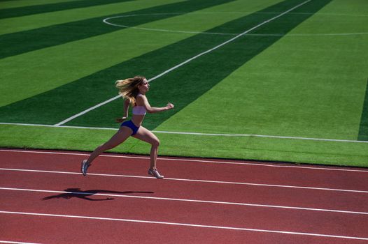 Young caucasian woman is engaged in jogging at the stadium outdoors.