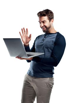 Hi Can you see me. Studio shot of a handsome young man using a laptop and waving against a white background.