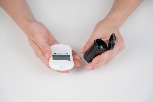 Woman measures blood sugar level with a glucometer.