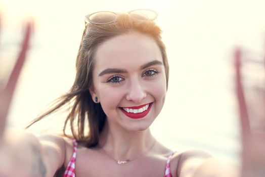 Taking a selfie by the sea is a must. Portrait of a beautiful young woman taking a selfie at the beach.