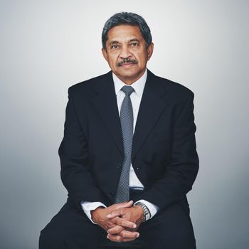 Hes experienced in his field. Studio portrait of a mature businessman posing against a grey background.
