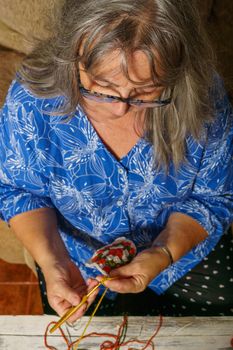 older white-haired woman crocheting