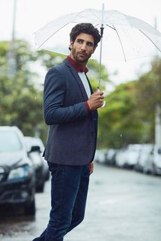 The rain wont keep him away from work. a handsome young businessman on his morning commute in the rain.