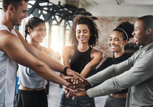 Gym fans unite. a group of young people joining their hands together in solidarity at a gym.