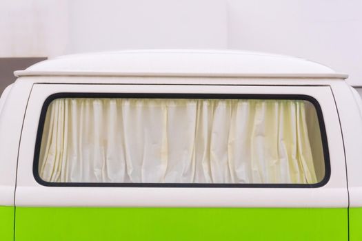 Curtained window of a bright white and green travel van