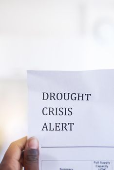 Be aware of the drought. Closeup of an unrecognizable person holding a paper with a notification on it saying drought crisis alert.