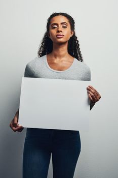 Be strong in all that you pursue. Studio shot of an attractive young woman holding a blank placard against a grey background.