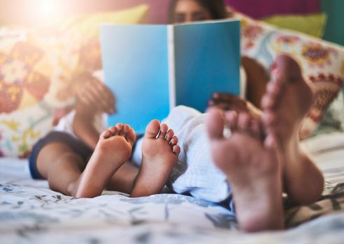 Chilling with a relaxing read. Closeup shot of a mother and her little daughters bare feet at home.
