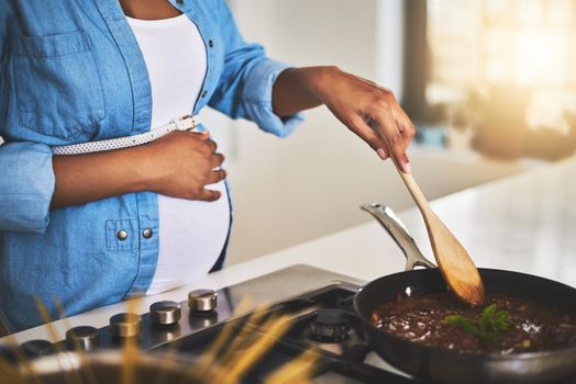 Some home cooked loving for baby bump. a pregnant woman preparing a meal on the stove at home.