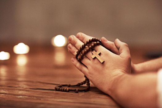 Person hands praying holding a rosary with cross of Christian faith, religion or tradition in a religious church closeup and background. Man Catholic church with prayer hands and spiritual devotion
