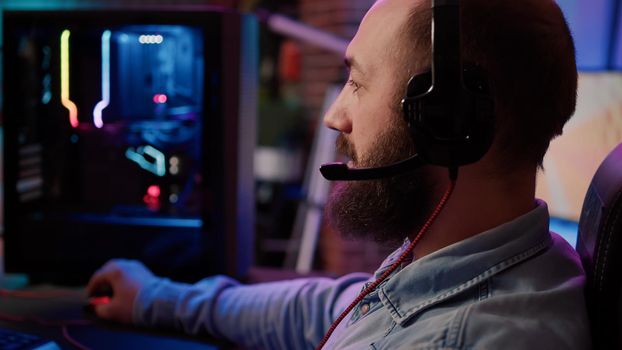 Extreme closeup of man using headset talking into microphone with team while playing first person shooter