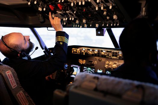 Male captain pushing buttons to start power on dashboard control