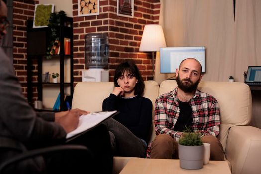 Portrait of unhappy couple talking to counselor at therapy session