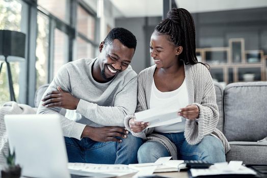 Happy black couple paying bills on a laptop at home, checking their budget and savings. Smiling African american husband and wife enjoying future planning, excited about an investment and good credit