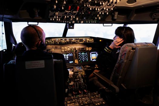Team of airliner and captain using power switch on cabin dashboard
