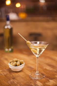 Celebration with a glass of white martini and olives in a restaurant at the bar counter. Club drink. Fresh drink.