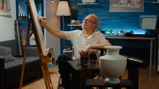Old man with physical disability using artistic tools to draw vase