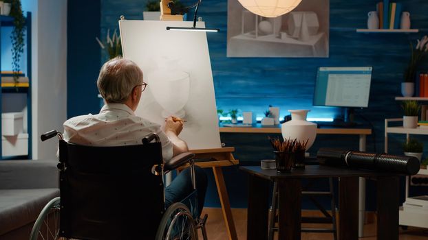 Senior adult with chronic impairment using pencils to draw vase