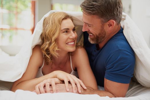 Your smile is my everything. a happy middle aged couple relaxing in bed together.