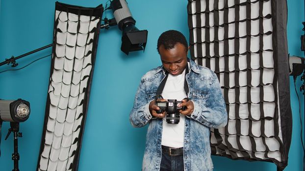 Photographer looking at dslr camera to check image in studio