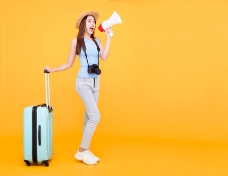 Happy young woman with luggage and holding megaphone isolated on yellow background ,summer,travel concept.