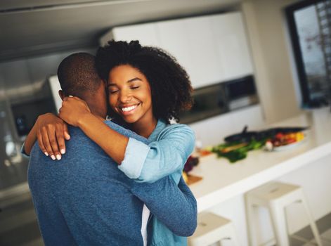 I want to stay like this forever. a cheerful young couple holding each other and sharing a tender moment in the kitchen at home during the day.