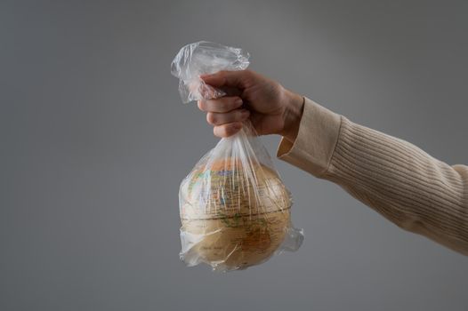 A woman is holding a globe in a plastic bag on a white background.