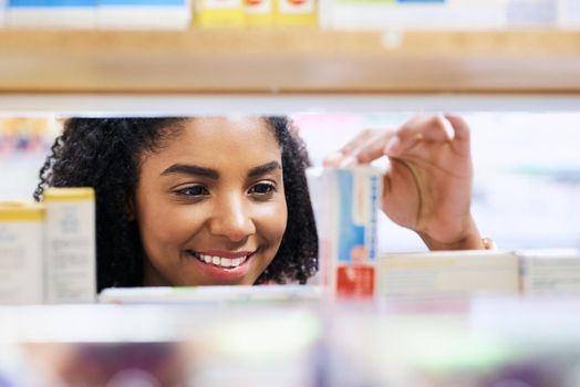 They always have stock of the medication I need. a young woman looking at products in a pharmacy.