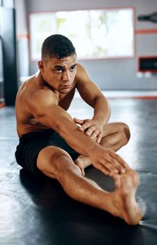 Stretching helps with staying in top form. a young man stretching before a fight at the gym.