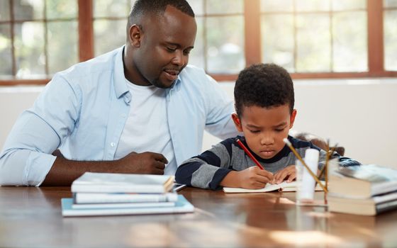 Dads here if you get stuck. a handsome young father helping his son with some homework.