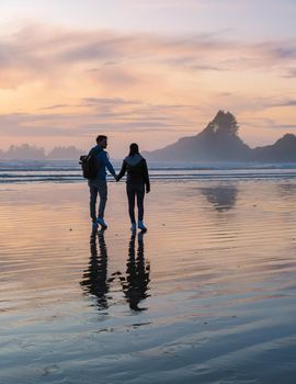 couple of men and women mid-age watching the sunset on the beach of Tofino Vancouver Island