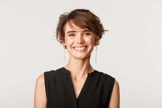 Close-up of stylish smiling businesswoman looking happy at camera, standing over white background