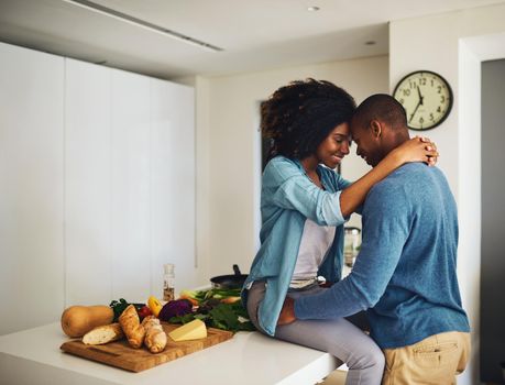 We have to get back to work. a cheerful young couple holding each other and sharing a tender moment in the kitchen at home during the day.