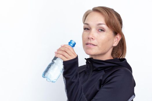 Woman holding plastic bottle of water on white background