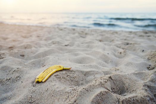banana peel lying on the sand beach. beach pollution