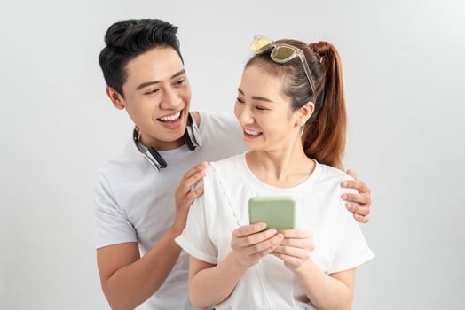 Image of cheerful man smiling while looking at cellphone of his girlfriend isolated overwhite background