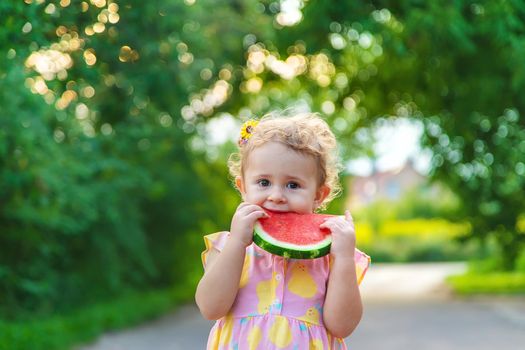Child girl eats watermelon in summer. Selective focus.