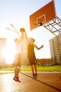 Two guy play basketball at district sports ground.