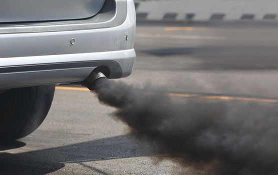 Air pollution from vehicle exhaust pipe on road.