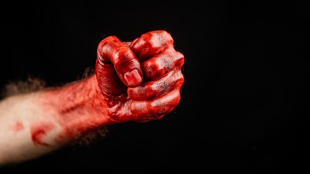 Bloody male fist on a black background.
