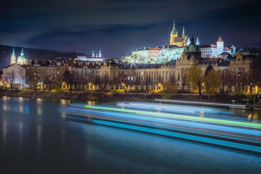 Hradcany, St Vitus Cathedral and Vltava river at night with blurred boat, Prague