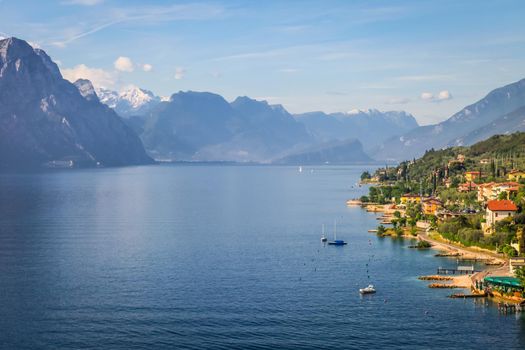Above idyllic Lake Garda with sailboats in Malcesine at sunrise, Italian alps