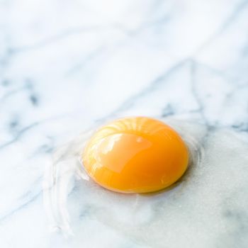 egg yolk on marble - recipe ingredients and homemade cooking concept