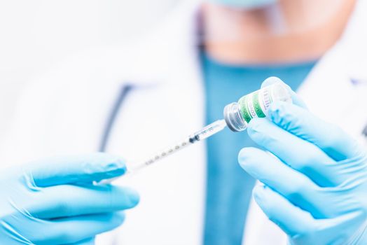 Doctor man pull syringe on liquid bottle COVID-19 (coronavirus) vaccine for injection at hospital