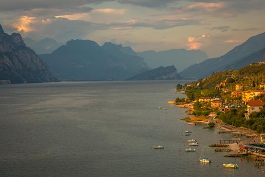 Above idyllic Lake Garda with sailboats in Malcesine at sunset, Italian alps