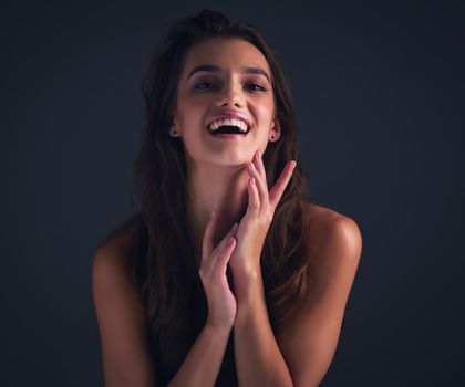 Happiness looks great on her. Studio shot of an attractive young woman posing against a dark background.