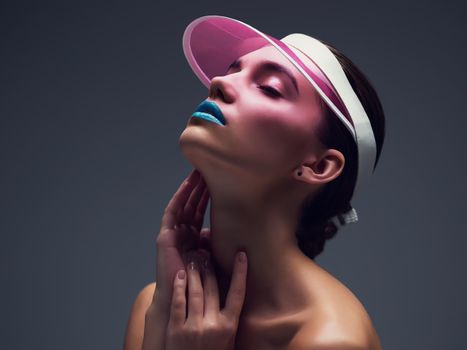 She was born to stand out. Studio shot of an attractive young woman wearing a pink retro cap posing against a gray background.