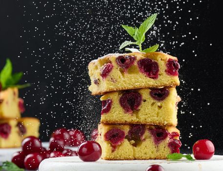 Baked sponge cake with cherries sprinkled with powdered sugar